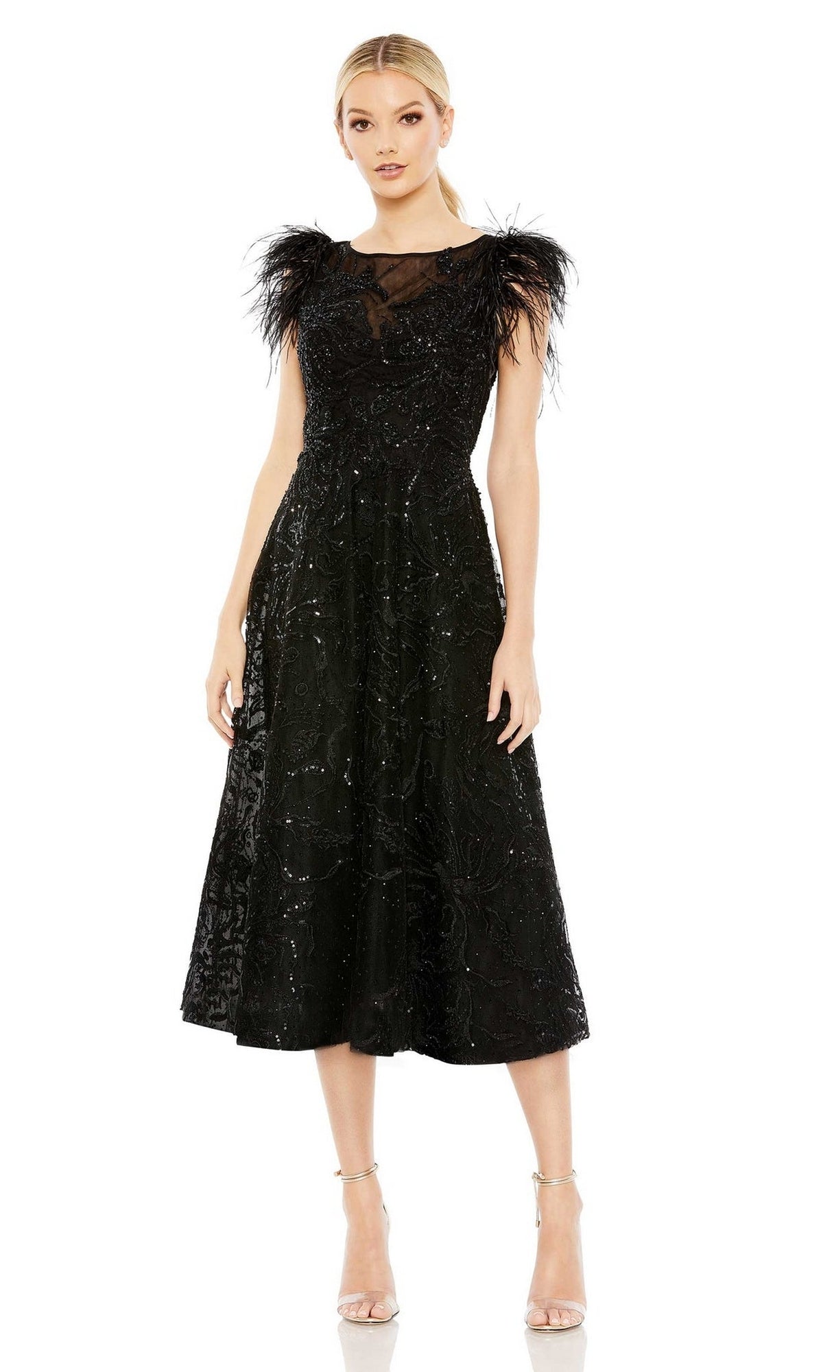 A woman stands facing forward in the Mac Duggal 20400 Black Sequin Wedding Guest Dress, a midi black party dress with sequin details and feathered shoulders, paired with strappy heels.